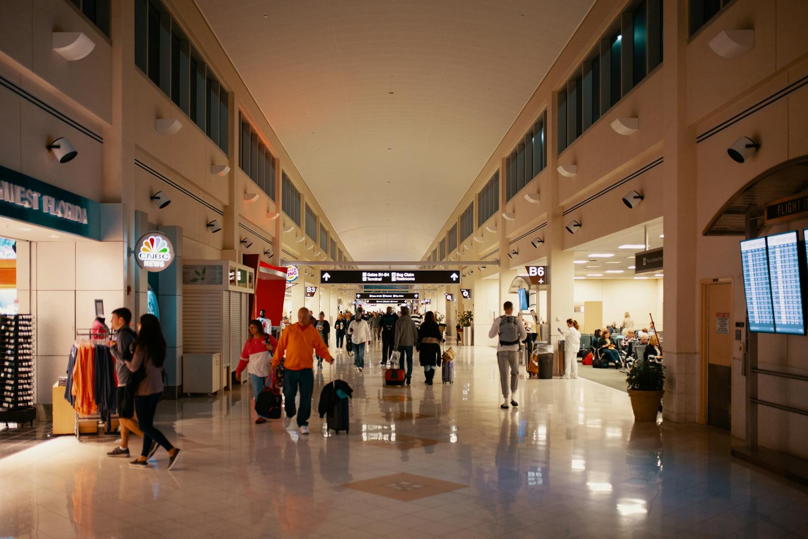 Crowds navigating a bright and busy airport terminal hallway, capturing travel dynamics indoors.